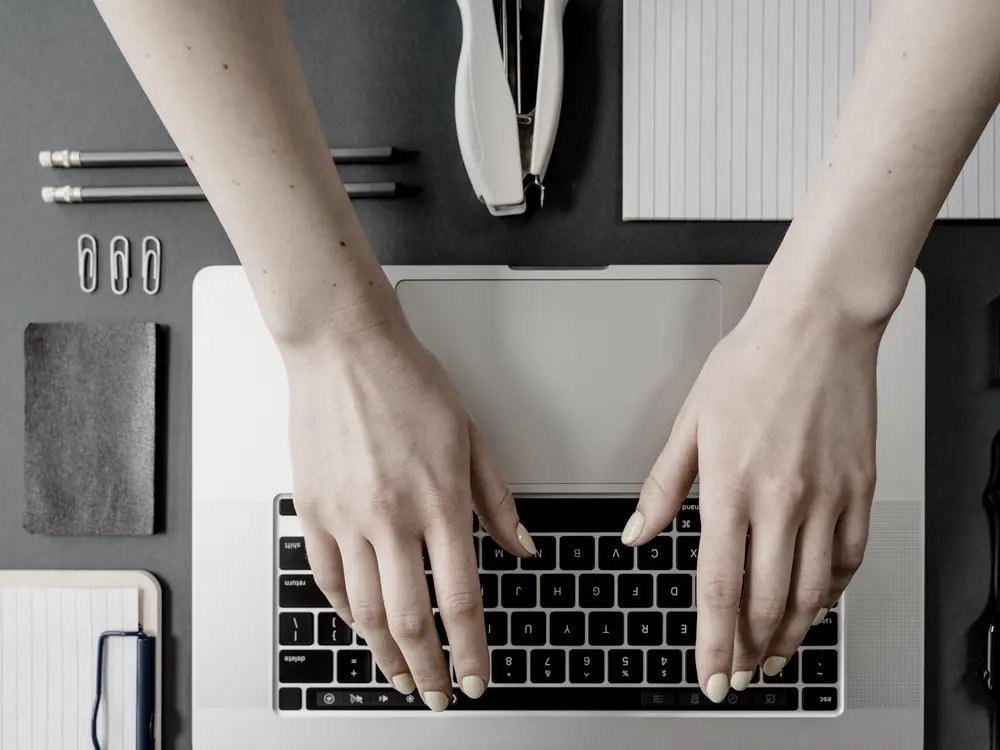 Hands typing on a laptop keyboard